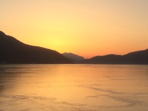 Islag fjord med solnedgang i oransje glød