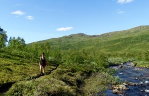 Dame går tur ved elva oppover Inderdalen