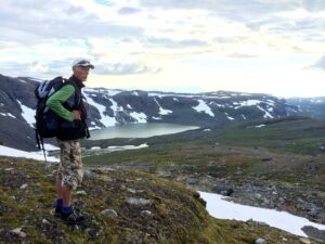 Mann med ryggsekk ser utover fjellheimen